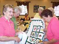 The Piecemakers are admiring Sue's latest Applique Quilt.