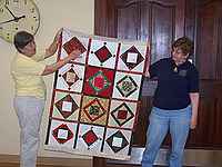 Gay Nocella showing Beth Bender the Blotto Quilt she made.