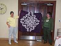 Joanne Carls showing her beautiful Hawaiian Applique Quilt.